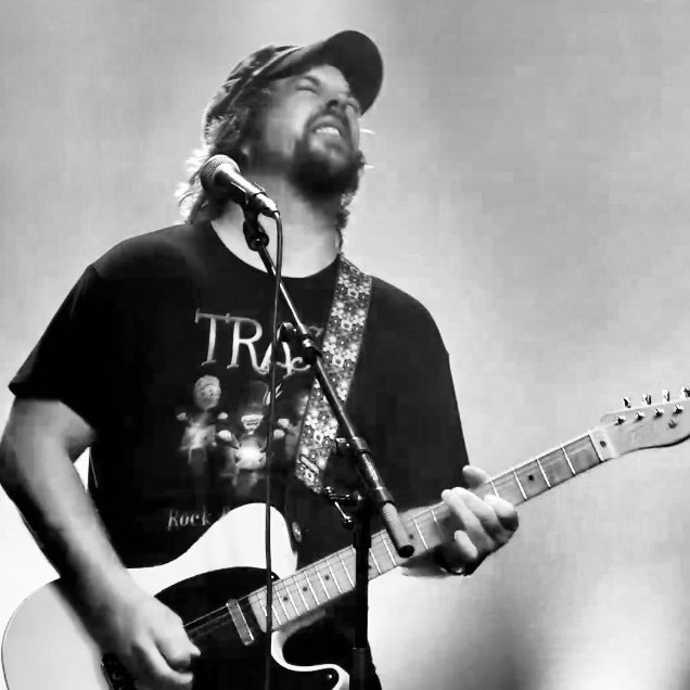 Gitarist i TRASS synger inn i mikrofonen på scenen